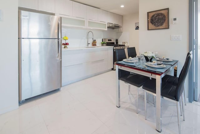 kitchen featuring under cabinet range hood, stainless steel appliances, modern cabinets, and a sink