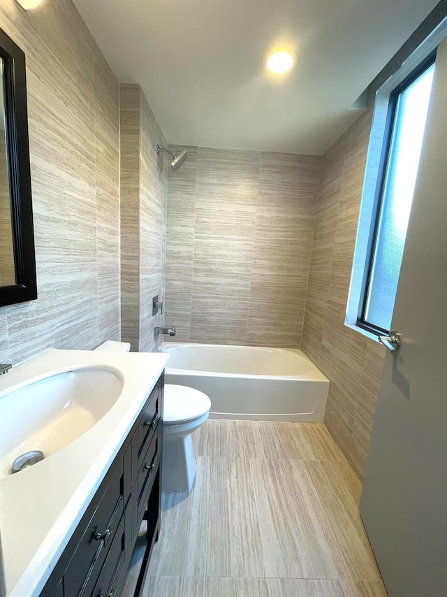 bathroom with shower / bath combination, toilet, tile walls, and vanity