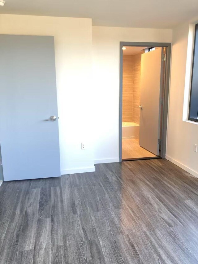 unfurnished bedroom with baseboards and dark wood-style flooring