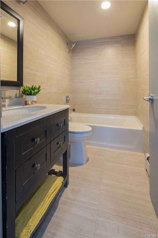 bathroom with vanity, a baseboard radiator, tile patterned flooring, shower / tub combination, and toilet