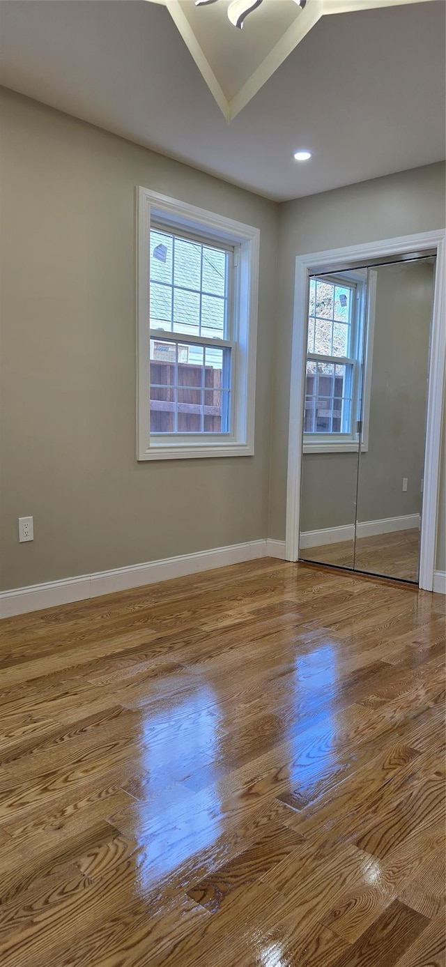 unfurnished bedroom with wood finished floors, baseboards, and a closet