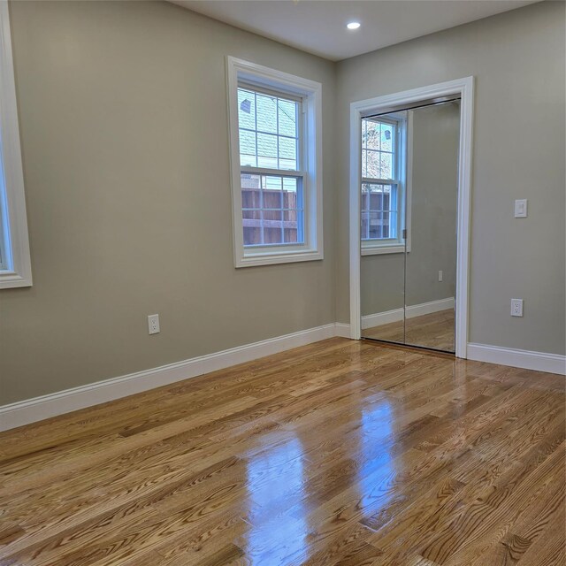 unfurnished bedroom featuring recessed lighting, wood finished floors, baseboards, and a closet