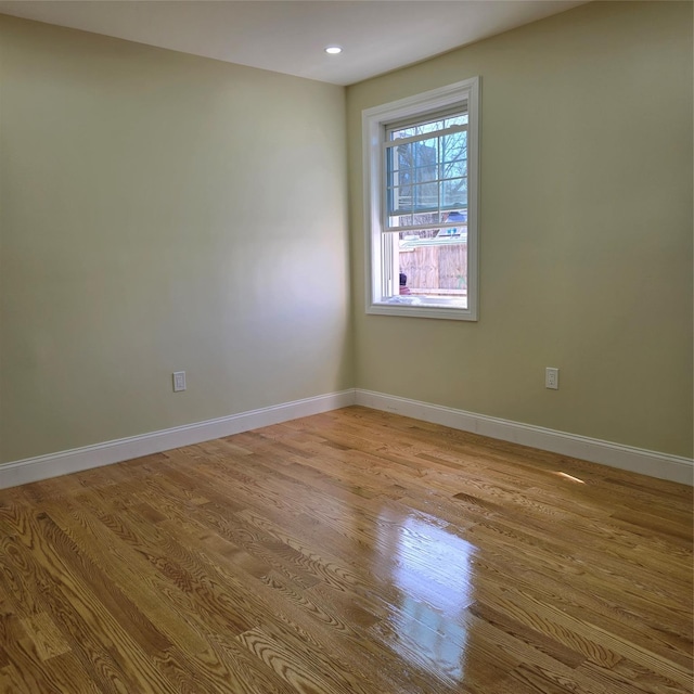 spare room featuring recessed lighting, baseboards, and wood finished floors