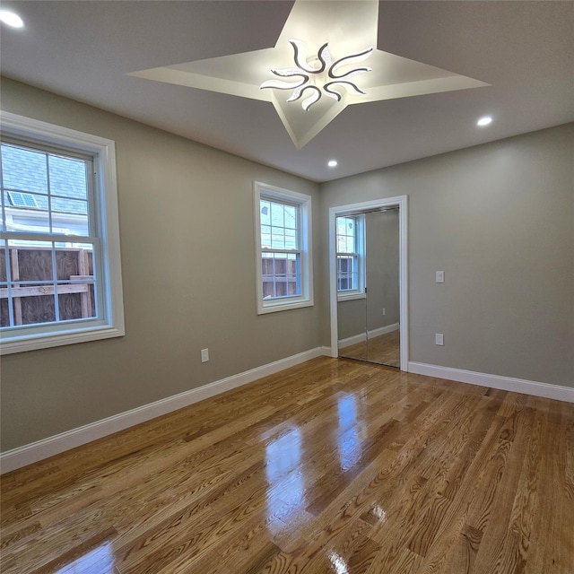 unfurnished bedroom with recessed lighting, a closet, baseboards, and wood finished floors