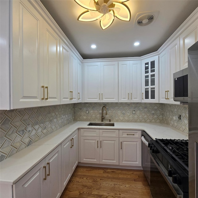 kitchen featuring a sink, stainless steel microwave, white cabinetry, and black gas stove