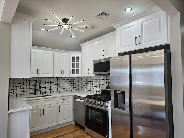 kitchen with visible vents, a sink, white cabinetry, light wood-style floors, and appliances with stainless steel finishes