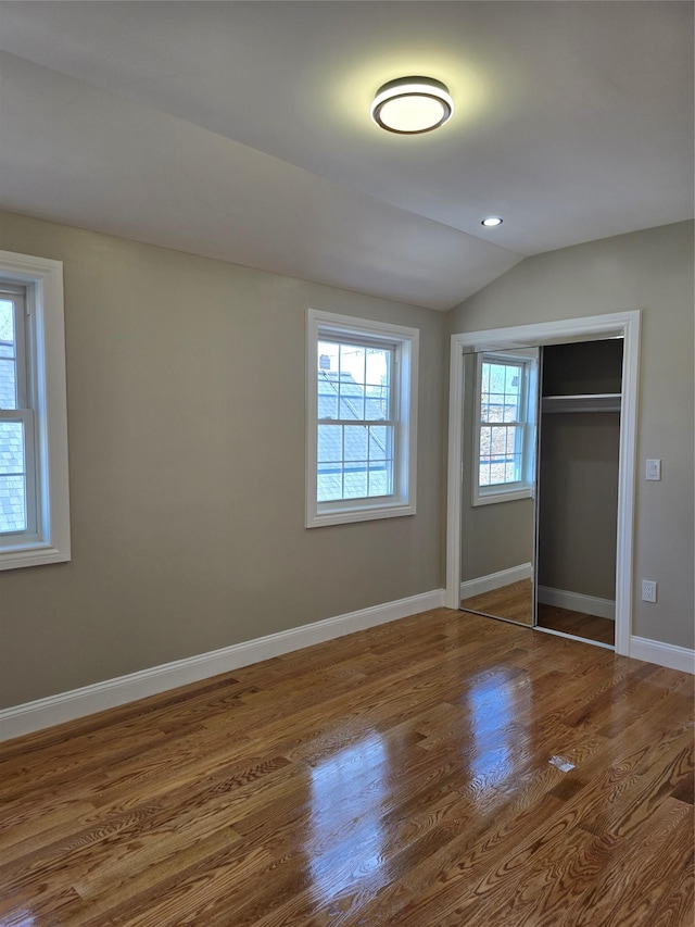 unfurnished bedroom featuring lofted ceiling, wood finished floors, recessed lighting, a closet, and baseboards