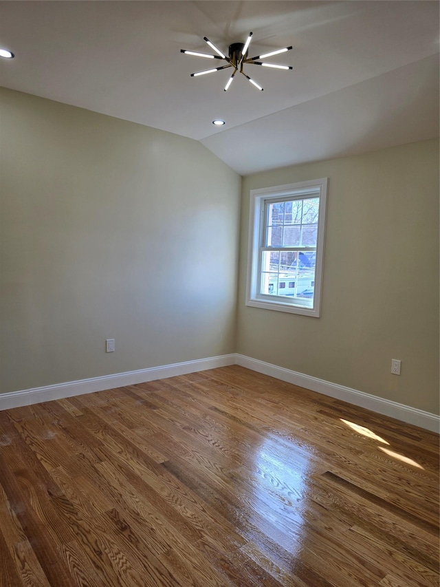 empty room featuring baseboards, lofted ceiling, and wood finished floors