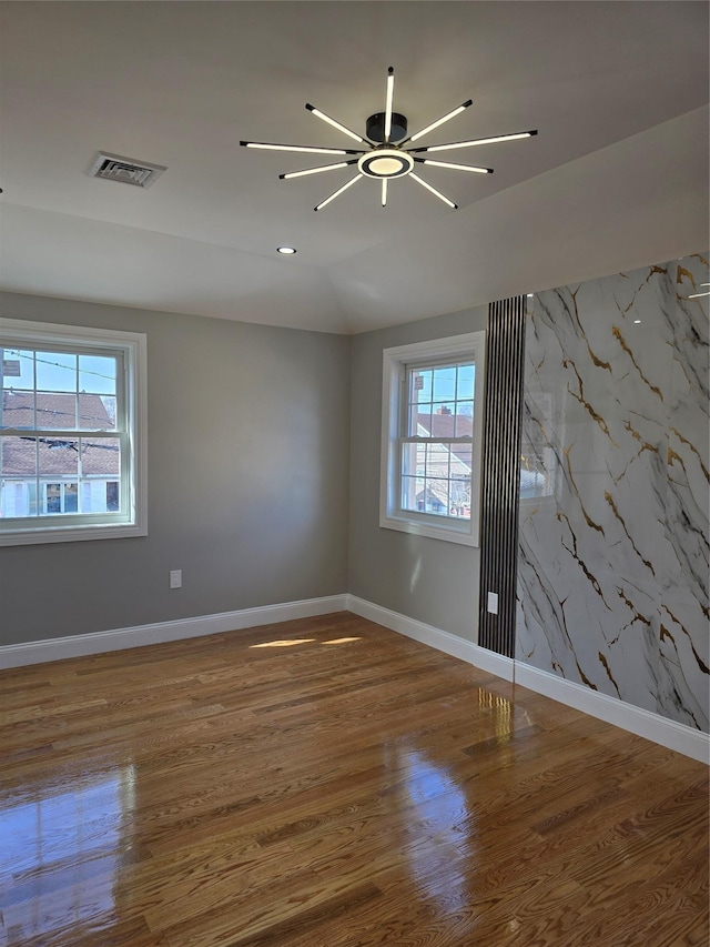 empty room with wood finished floors, visible vents, baseboards, lofted ceiling, and ceiling fan