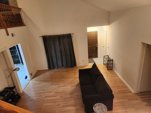 sitting room with light wood-style floors, baseboards, and high vaulted ceiling