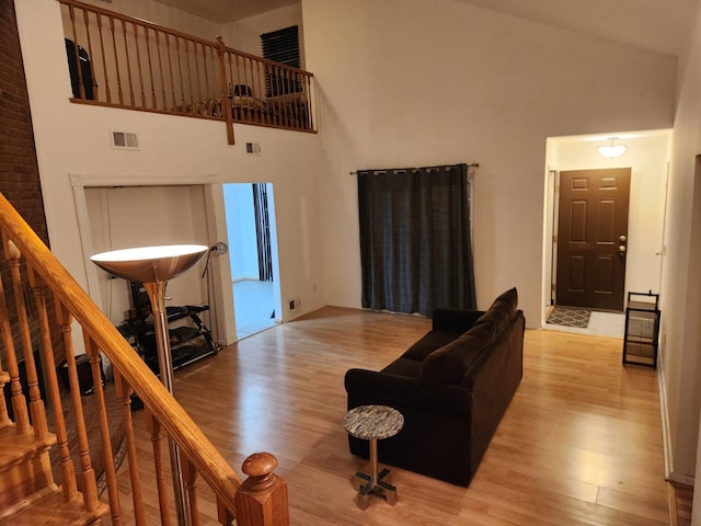 living room with stairway, visible vents, light wood finished floors, and high vaulted ceiling