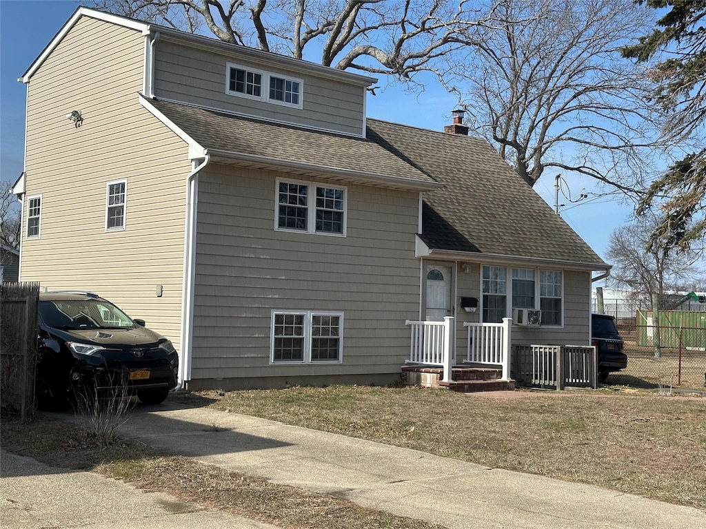 view of front of home featuring driveway, fence, a chimney, and a shingled roof