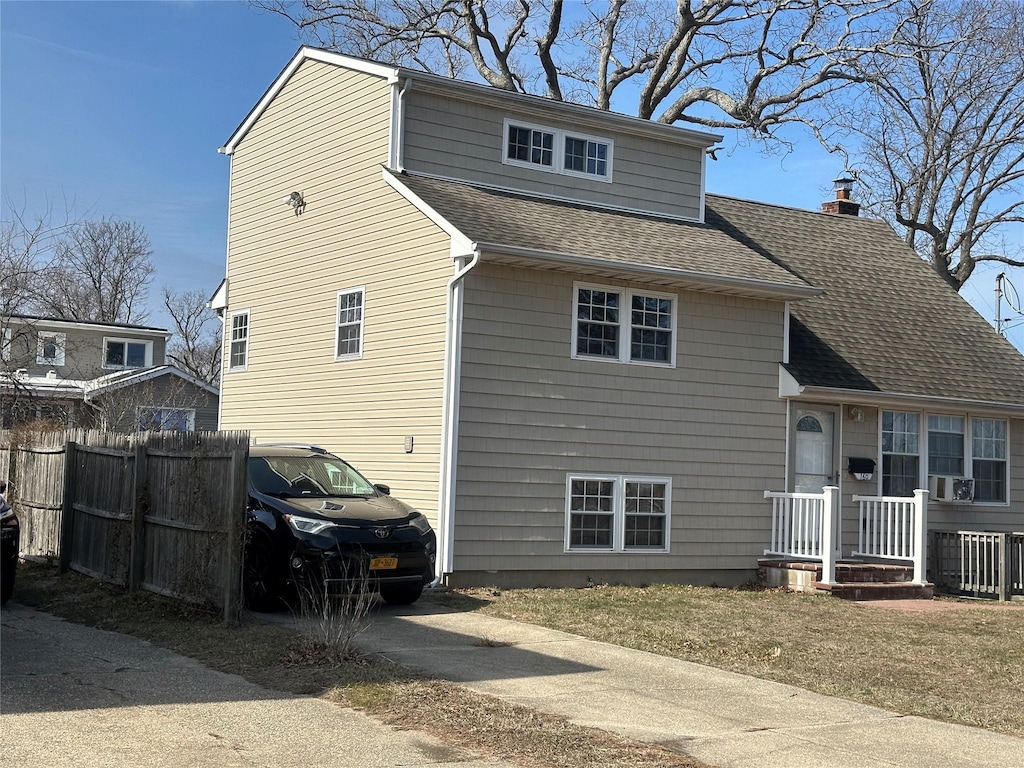 view of front of property with concrete driveway, fence, a chimney, and a shingled roof