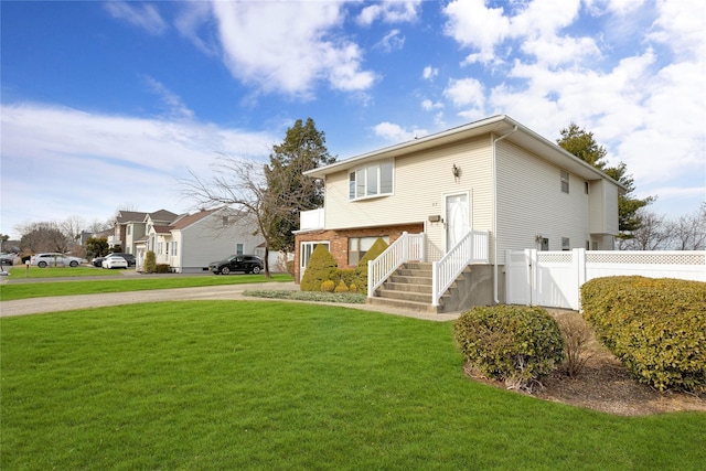 rear view of property featuring a gate, a lawn, and fence