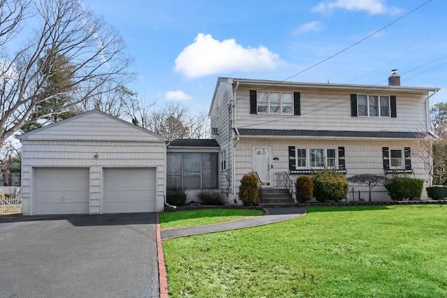 traditional-style house with aphalt driveway, an attached garage, a chimney, and a front lawn