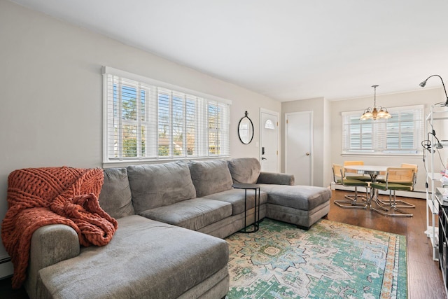 living area with baseboard heating, an inviting chandelier, and wood finished floors