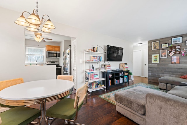 living room featuring ceiling fan with notable chandelier and wood finished floors