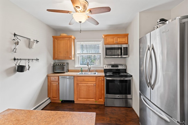 kitchen featuring a ceiling fan, a baseboard radiator, a sink, light countertops, and appliances with stainless steel finishes