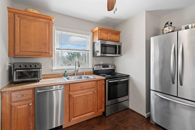 kitchen featuring ceiling fan, light countertops, appliances with stainless steel finishes, dark wood-style floors, and a sink