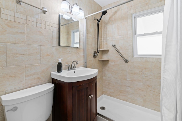 full bath with tile walls, toilet, tiled shower, and vanity