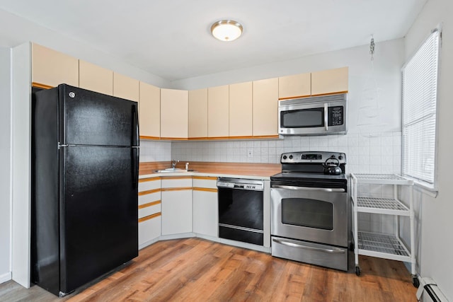 kitchen featuring a baseboard heating unit, black appliances, cream cabinetry, and light countertops