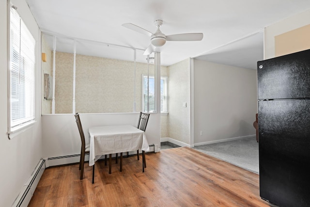 dining space featuring baseboards, a baseboard heating unit, a ceiling fan, and wood finished floors