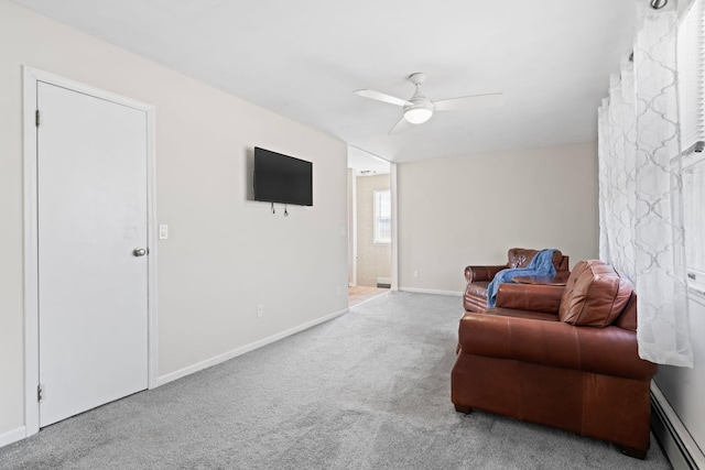 living area with baseboard heating, carpet flooring, baseboards, and a ceiling fan