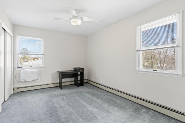 spare room featuring a ceiling fan, a healthy amount of sunlight, light colored carpet, and baseboard heating