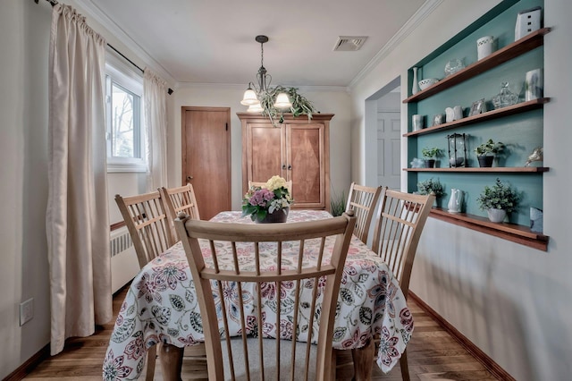 dining room with visible vents, wood finished floors, an inviting chandelier, and ornamental molding