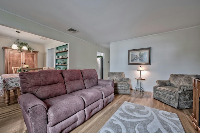 living room with visible vents, light wood-style flooring, and crown molding