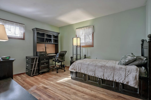 bedroom featuring multiple windows, wood finished floors, and baseboards