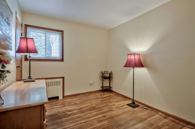 interior space featuring radiator heating unit, baseboards, and wood finished floors