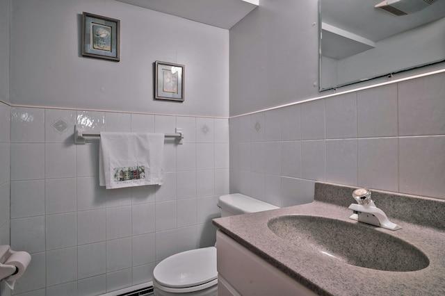 half bathroom featuring visible vents, vanity, toilet, and tile walls