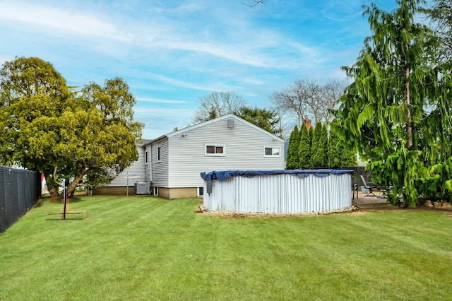 back of property featuring a covered pool, a yard, and fence