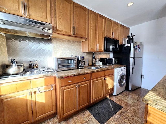 kitchen featuring under cabinet range hood, a sink, washer / clothes dryer, appliances with stainless steel finishes, and a toaster