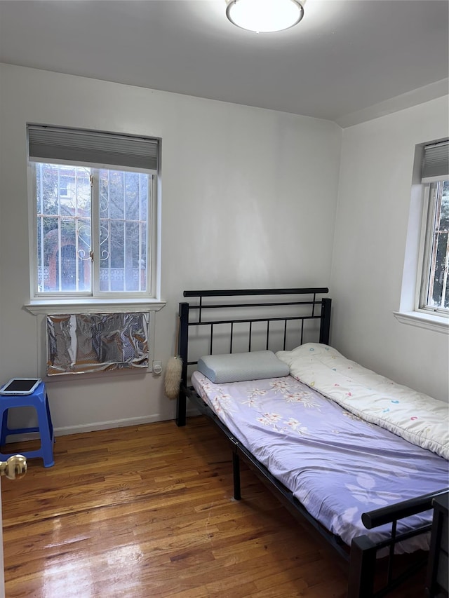 bedroom with multiple windows and wood finished floors