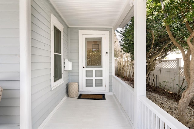 property entrance with covered porch and fence