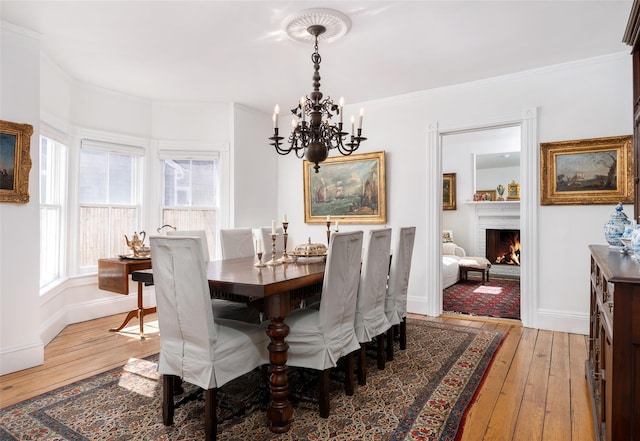 dining space featuring light wood-type flooring, baseboards, a brick fireplace, and crown molding