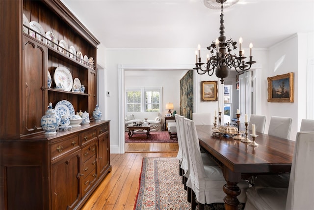 dining space featuring a notable chandelier, light wood-style floors, and ornamental molding