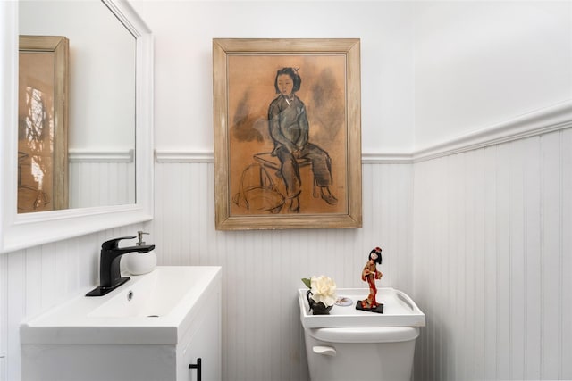 bathroom featuring toilet, wainscoting, and vanity