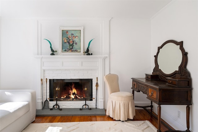 sitting room featuring a fireplace, crown molding, and wood finished floors