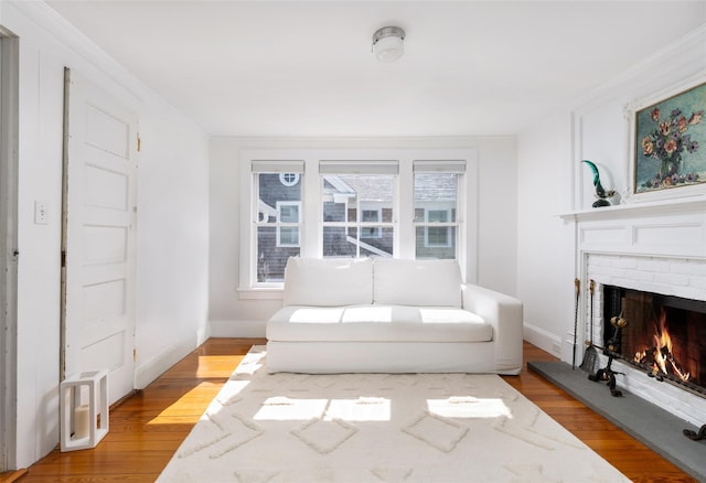 living area with baseboards, light wood-style floors, and a brick fireplace