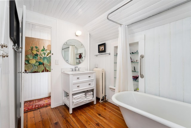 bathroom with hardwood / wood-style flooring, radiator, wooden ceiling, a soaking tub, and vanity