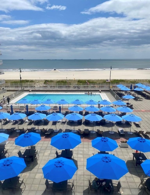 pool with a patio area, a view of the beach, and a water view