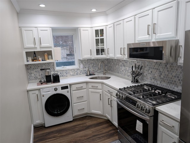 kitchen with ornamental molding, a sink, washer / clothes dryer, dark wood-style floors, and stainless steel appliances