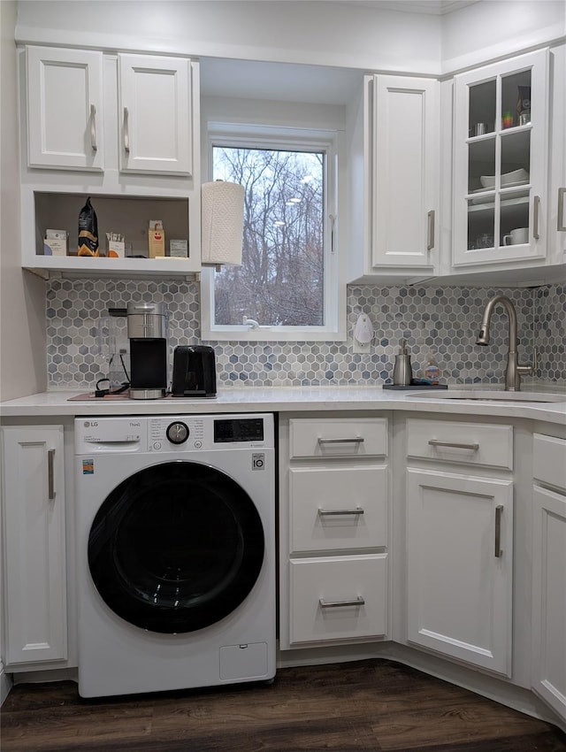 laundry area featuring dark wood finished floors, washer / clothes dryer, cabinet space, and a sink