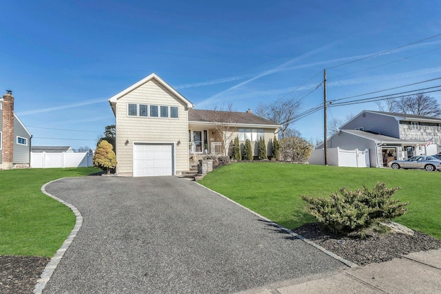 tri-level home featuring a front lawn, fence, covered porch, and driveway