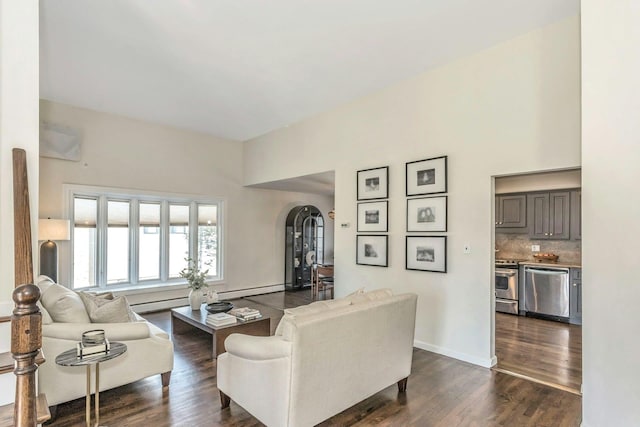 living area with arched walkways, dark wood-type flooring, baseboards, and a baseboard radiator