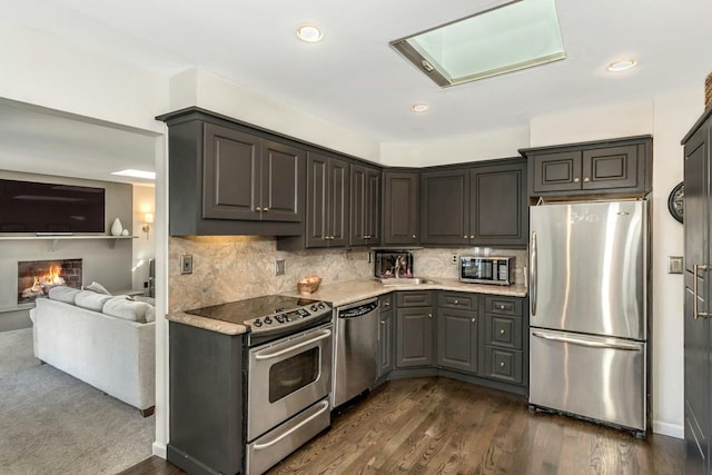 kitchen featuring light countertops, backsplash, dark wood-style floors, and appliances with stainless steel finishes