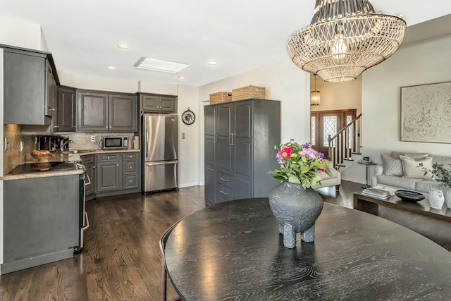 dining space with baseboards, an inviting chandelier, a skylight, recessed lighting, and dark wood-type flooring